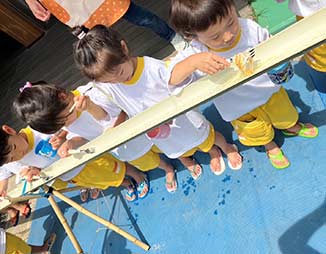 子どもたちが黄色い靴を履いて座り、活動や訓練を行っている風景